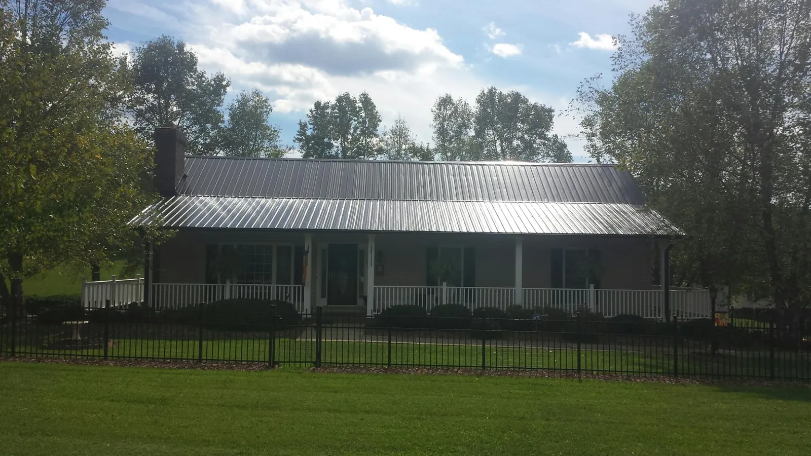 Gray metal roof on a brick ranch with a full width front porch — Gutter Guard Installation work by our crew in Toddville