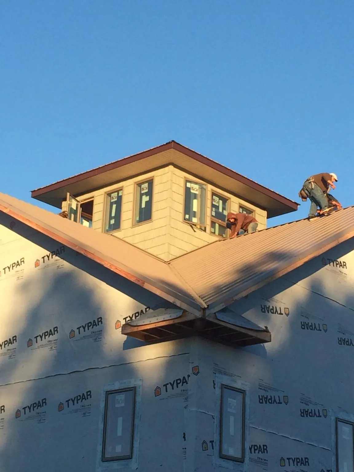 Roofers working around a rooftop cupola on a new metal roof at sunset — Roof Waterproofing in Toddville by Roofing Brothers